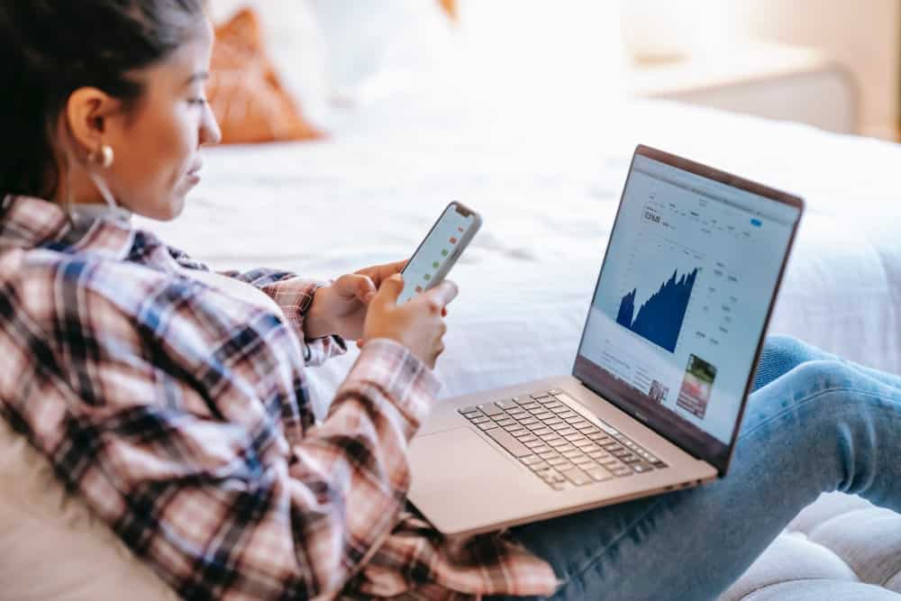 a woman looking at a website in her handphone and laptop illustrating guide to website localization for business owners