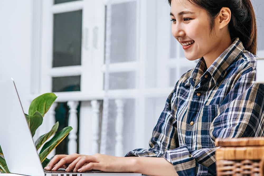 A copywriter writing on a copy in front of her laptop illustrating the importance of copywriting services