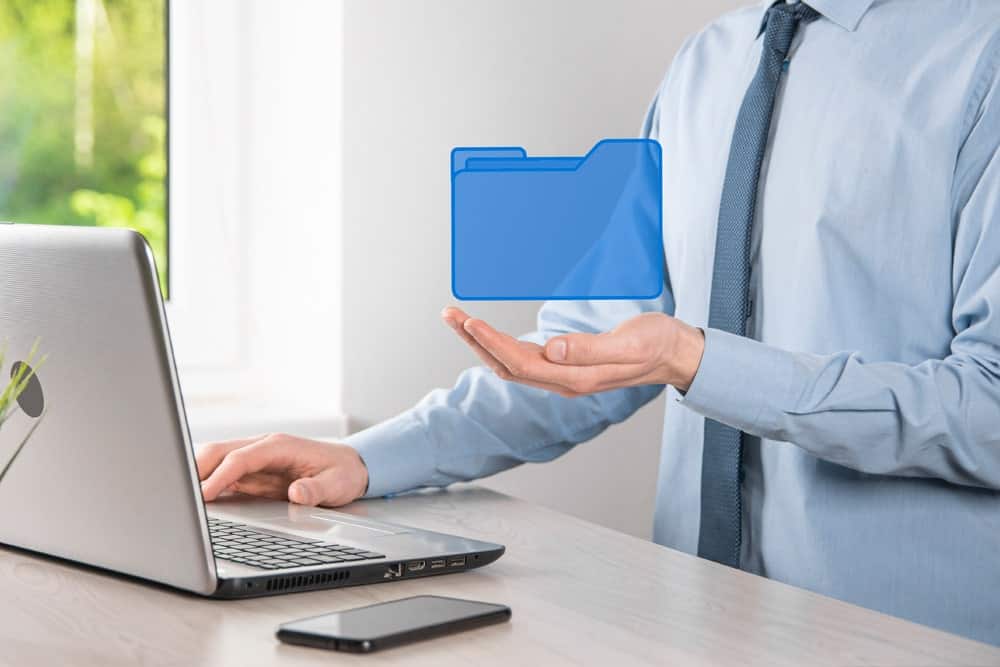 An office worker writing on laptop with a virtual file illustrating the importance of copywriting services