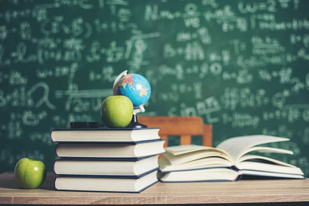 A green apple and globe on top of books illustrating the importance of Translation Services