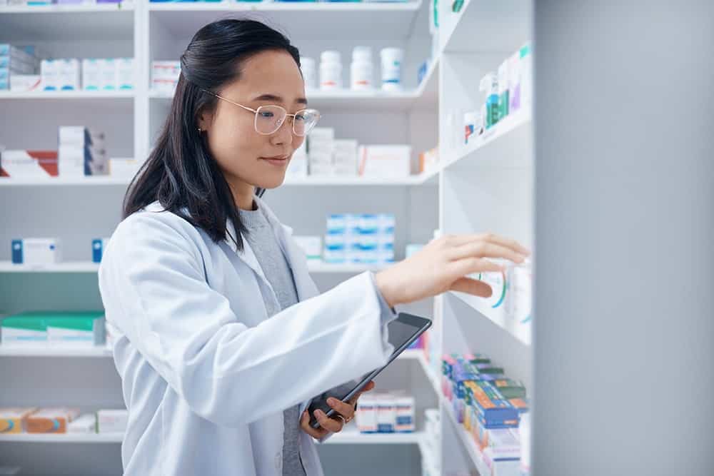 A pharmacist taking medicines from a shelf illustrating the importance of medical document translation services