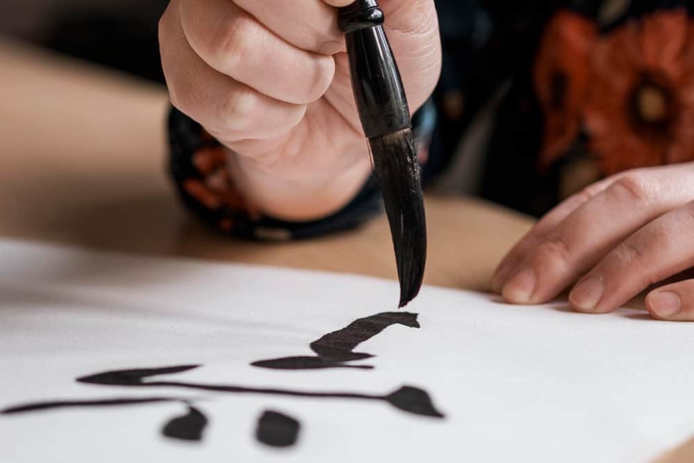 A man writing Chinese text in calligraphy illustrating the importance of Chinese translation services