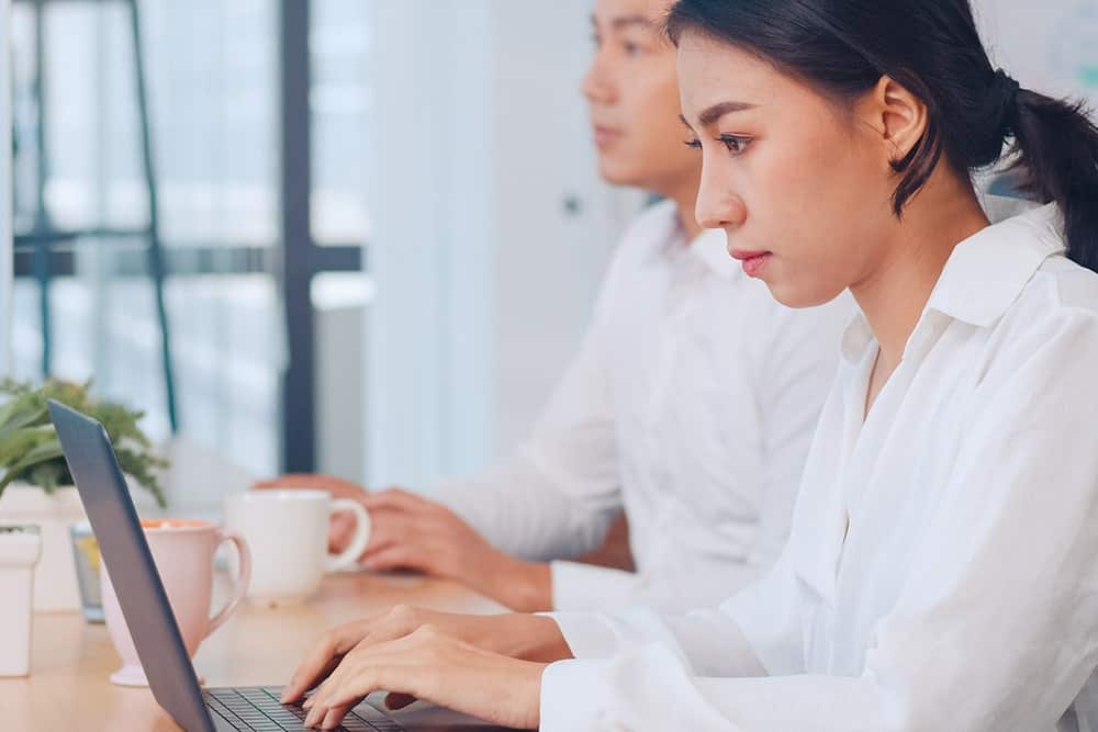 A woman typing on a laptop working on a translation service project